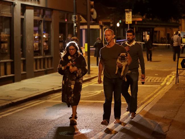 A man carries a dog with a woman wearing a dressing gown after an attack in London. Picture: AP