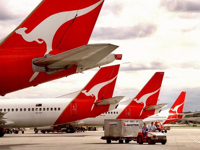 Qantas aircraft tails at Kingsford Smith Airport in Sydney as baggage handlers deliver luggage. plane airline logo tail/Qantas/Airways/Ltd