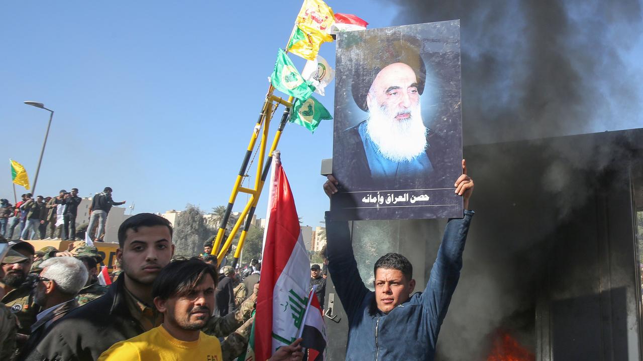 An Iraqi supporter of the Hashed al-Shaabi military network lifts a picture of Iraq's top Shi'ite cleric Grand Ayatollah Ali Sistani during a rally in front of the US Embassy. Picture: Ahmad Al-Rubaye/AFP