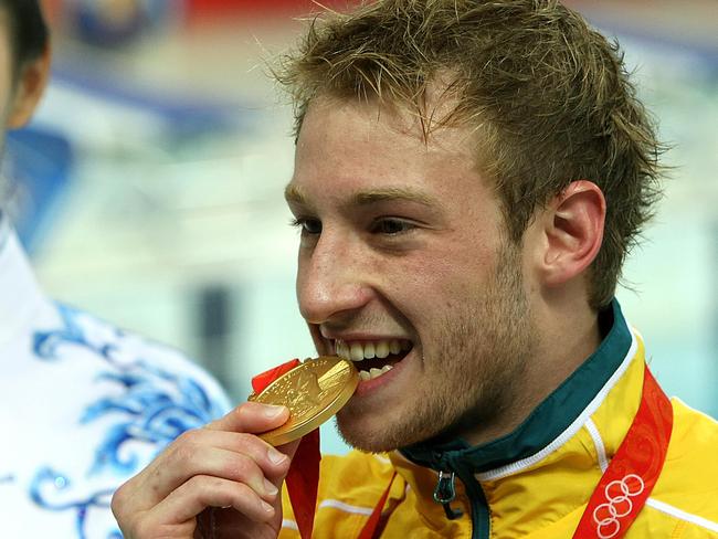 Matthew Mitcham of Australia (R) bites his gold medal he won for the final of the men's 10m platform diving at the 2008 Beijing Olympic Games on August 23, 2008. Mitchell won gold with a score of 537.95 points. AFP PHOTO / Greg WOOD