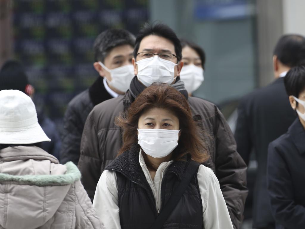 People wearing protective face masks cross a street in Tokyo on Monday. Picture: Koji Sasahara/AP