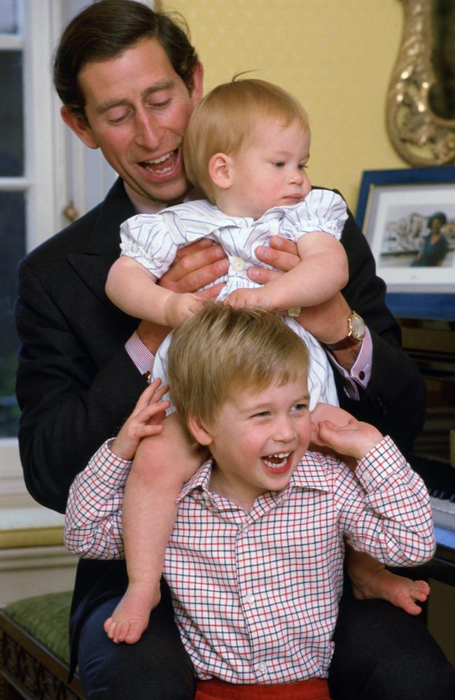 Prince Charles laughing with his young sons as he lifts Prince Harry onto Prince William's shoulders in Kensington Palace. Picture: Tim Graham Photo Library via Getty Images