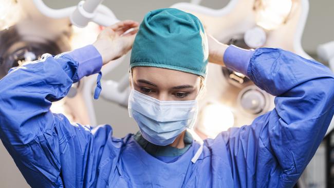 Female surgeon wearing surgical mask. Skilled doctor is working in operating room. She is in hospital.