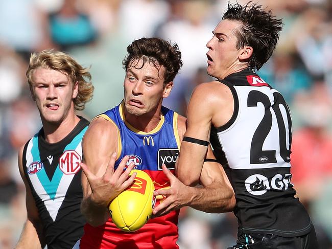 ADELAIDE, AUSTRALIA - MARCH 18: Josh Dunkley of the Lions under pressure from Connor Rozee of the Power and Jason Horne-Francis of the Power  during the 2023 AFL Round 01 match between the Port Adelaide Power and the Brisbane Lions at Adelaide Oval on March 18, 2023 in Adelaide, Australia. (Photo by Sarah Reed/AFL Photos via Getty Images)