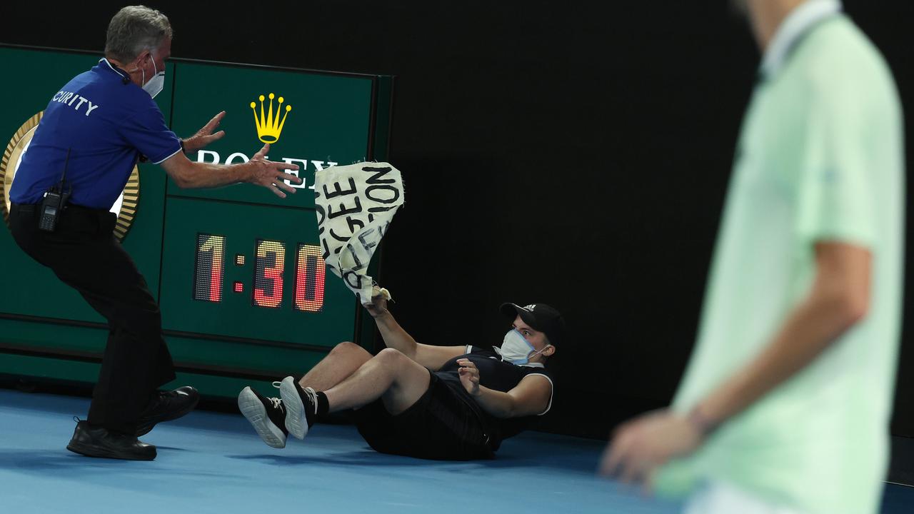 A protester jumped onto the court, falling to the ground, behind Daniil Medvedev. Picture: Michael Klein