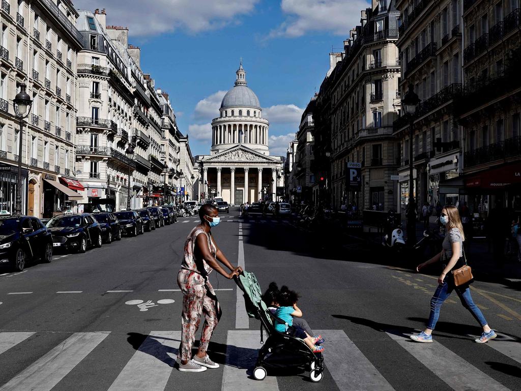 People wearing protective facemasks cross the rue Soufflot with the Pantheon in the background, in Paris, on May 19, 2020 as France eases lockdown measures. Picture: AFP