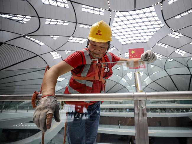 This photo taken on June 26, 2019 shows a worker cleaning a glass in the terminal building of the new Beijing Daxing International Airport in Beijing. - Beijing is set to open an eye-catching multi-billion dollar airport resembling a massive shining starfish, to accommodate soaring air traffic in China and celebrate the Communist government's 70th anniversary in power. (Photo by STR / AFP) / China OUT