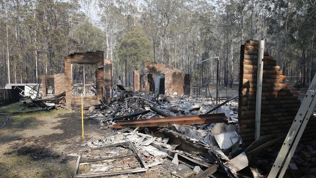 The remains of the residence at Four Paws boarding kennels smoulders along the Pacific Highway south of Taree on Saturday.