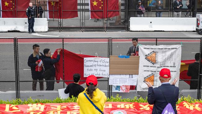 Chinese officials cover protest signs as supporters await the arrival of Xi Jinping next to APEC summit headquarters in San Francisco on Tuesday. Picture: AFP