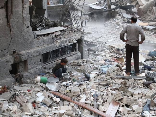 A Syrian boy collects items amid the rubble of destroyed buildings in Damascus. Picture: AFP