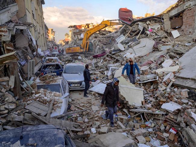 People walk across the rubble of collapsed building in Hatay province, southern Turkey where World Cup star Christian Atsu was found dead in rubble. Picture: AFP