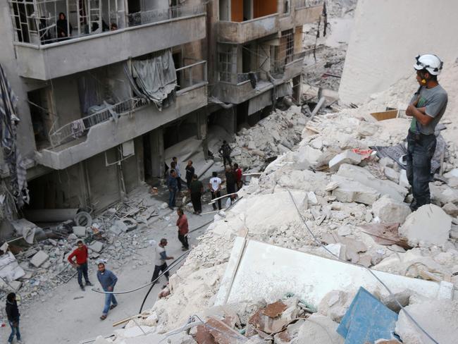 A Syrian civil defence volunteer, known as the White Helmets, stands on the rubble of destroyed buildings during a rescue operation following a government forces air strike on the rebel-held neighbourhood of Bustan al-Basha in the northern city of Aleppo. Picture: AFP