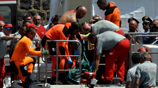 Divers carry the body of the last missing person at Porticello harbour near Palermo. Picture: AFP.