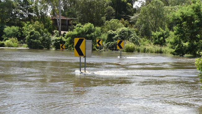 Waters surge at a flooded Youngs Crossing Road. Picture: Marcel Baum