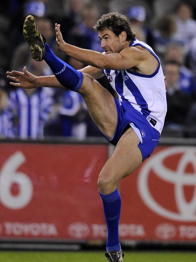 Nathan Thompson launches a goal for North Melbourne. 