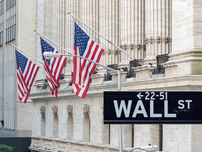 Wall Street sign with american flags and New York Stock Exchange in Manhattan, New York City, USA.