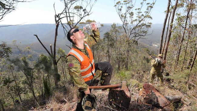 Defence force personnel cool off while working to clear maintenance tracks for firefighters in the Lower Beechmont area. Picture: Glenn Hampson