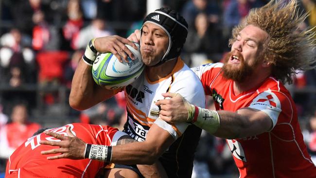 Brumbies' Christian Leali'ifano (C) is tackled by Sunwolves' Timothy Lafaele (L) and Willem Britz (R) during their Super Rugby match between Japan's Sunwolves and Australia's Brumbies at the Chichibunomiya Rugby Stadium in Tokyo on February 24, 2018. / AFP PHOTO / Toru YAMANAKA