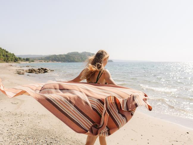 Photo of a young teenage girl walking down the beach, sunbathing, and enjoy warm summer breeze