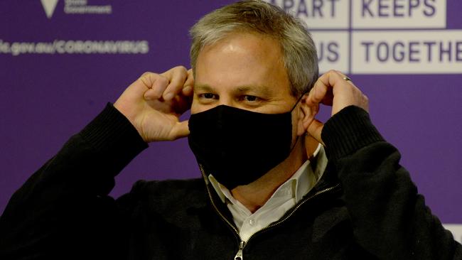 Chief Medical Officer Brett Sutton demonstrates how to put a mask on. Picture: Andrew Henshaw