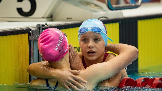 Girls 12-13 100m freestyle winner Charli Barbour (blue hat) being congratulated by second place Jaslyn Plummer (pink hat). Photo by Julian Andrews.