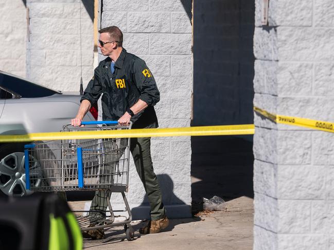 A member of the FBI pushes a shopping trolley at the site of the massacre. Picture: AFP.