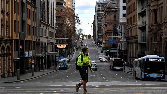 A man walking through the quiet streets of the near-deserted Sydeny CBD. (Photo by Saeed KHAN / AFP)