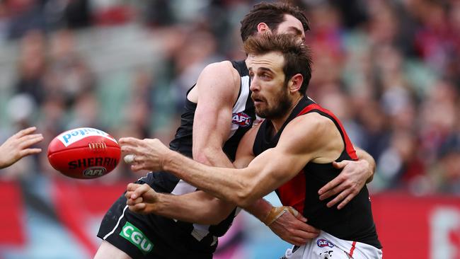 Tough in the clinches, Jobe Watson handballs before being crunched by Tyson Goldsack. Picture<b>:</b> Michael Klein.