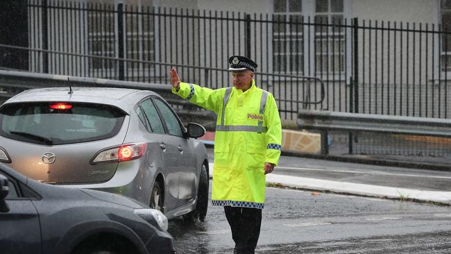 A police officer directs traffic through a flooded Vulture St in South Brisbane.