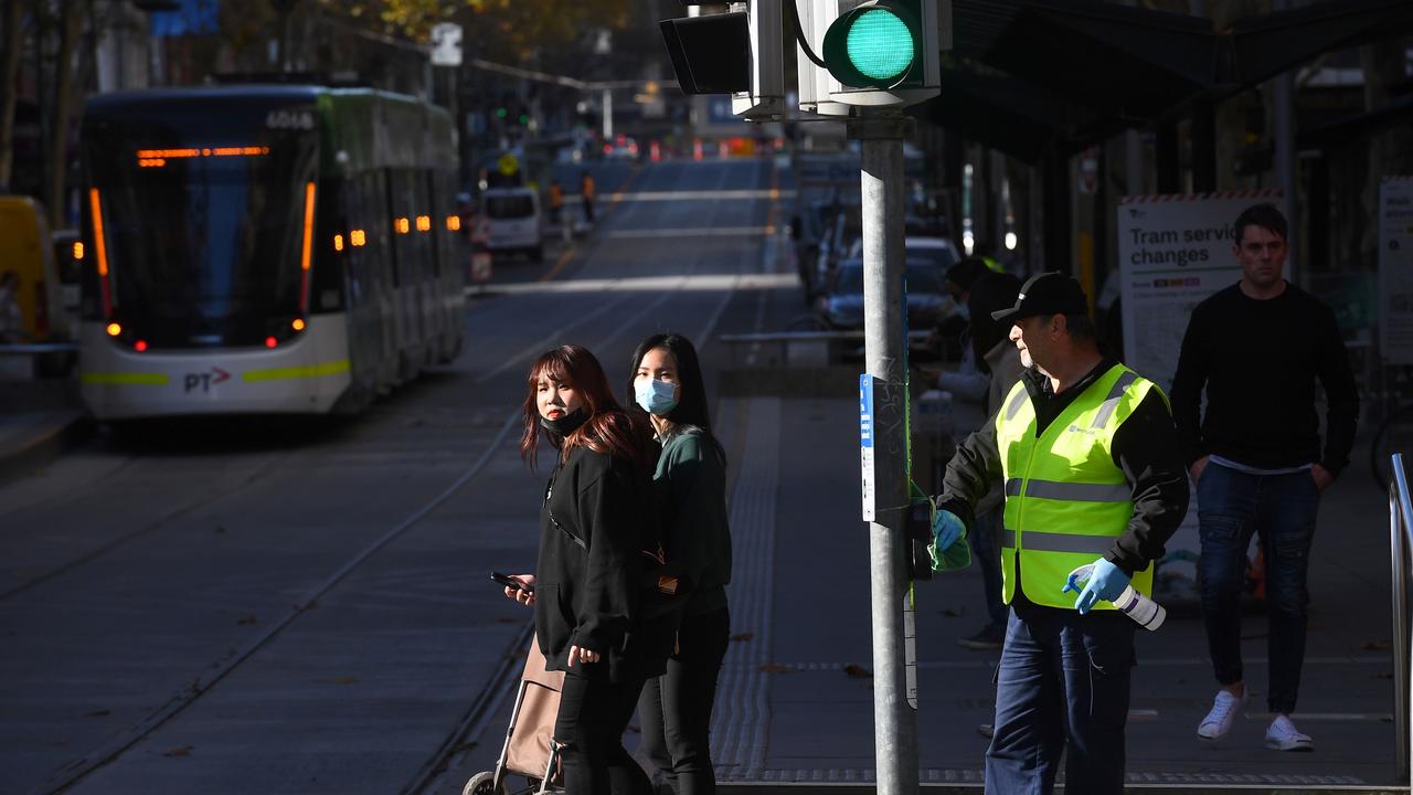 A cleaner wipes down a traffic light button in Melbourne. Picture: William West/AFP