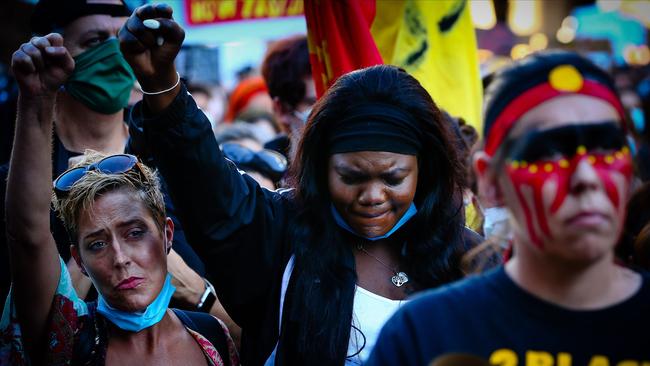 Priscilla Furight (left) and Maria Achan (centre) give a Black Power salute during rallies in Brisbane on Saturday. Picture: AFP