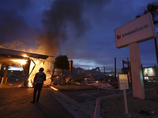 A man looks on as a bank burns in La Mesa, Calif. Picture: Gregory Bull)