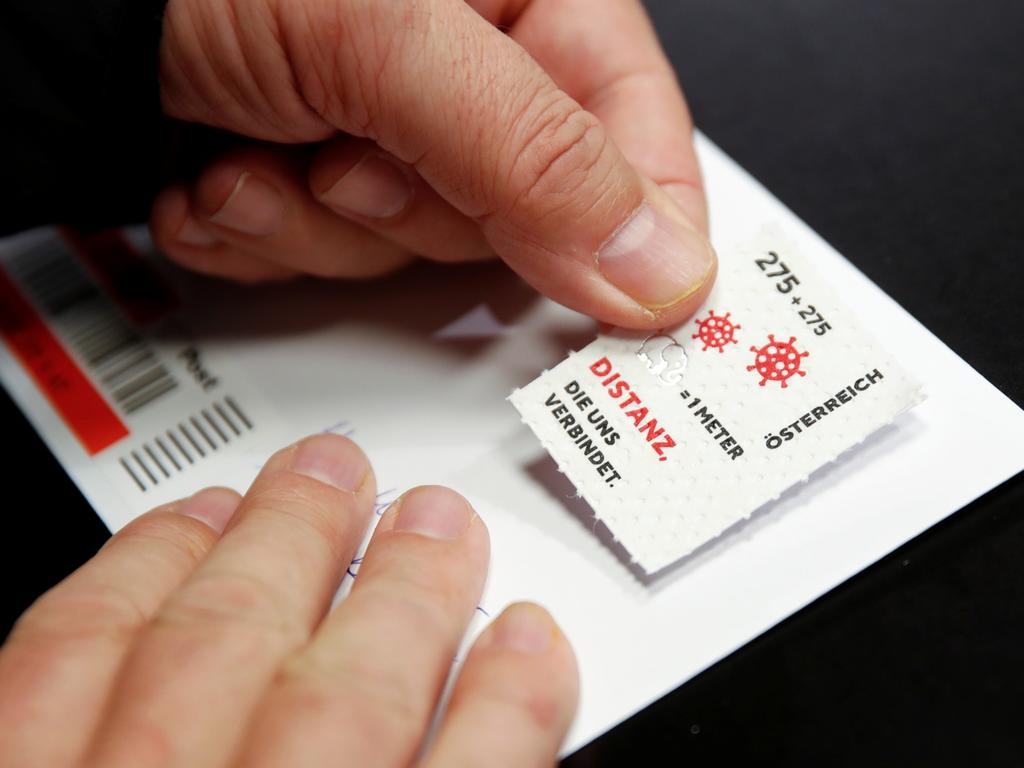 A customer puts a so-called "corona stamp" on a letter in a post office, as the 2.75 euro "corona stamp" is printed on three-ply toilet paper and sold individually as part of a 10 cm wide sheet, in Vienna, Austria October 23, 2020. REUTERS/Leonhard Foeger