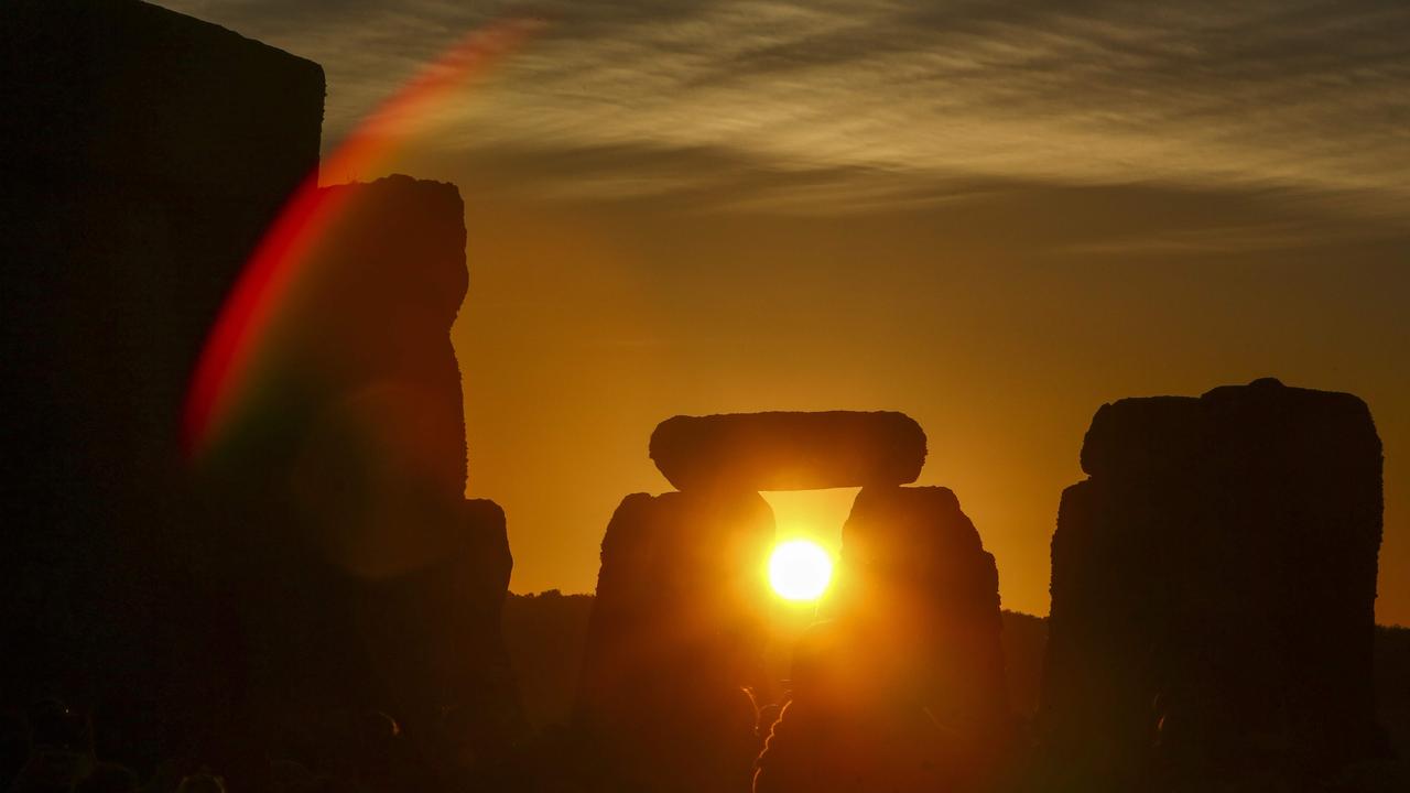 Revellers watch the sunrise as they celebrate the pagan festival of Summer Solstice at Stonehenge in Wiltshire, southern England on June 21, 2018. The festival, which dates back thousands of years, celebrates the longest day of the year when the sun is at its maximum elevation. Modern druids and people gather at the landmark Stonehenge every year to see the sun rise on the first morning of summer. / AFP PHOTO / Geoff CADDICK