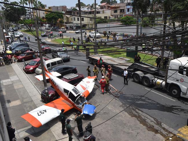 Fire fighters, police officers and members of the Air Force at the scene where a Peruvian Air Force training plane crashed on a street in Lima on February 4. Picture: AFP