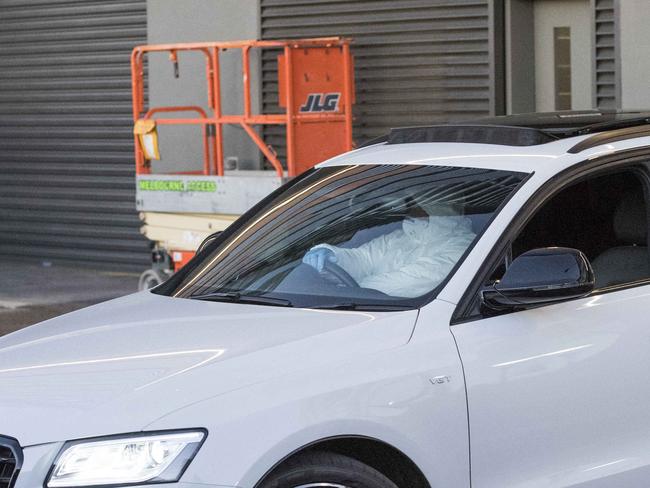 A man in protective gear drives an Audi out of a Docklands apartment block. Picture: Jason Edwards