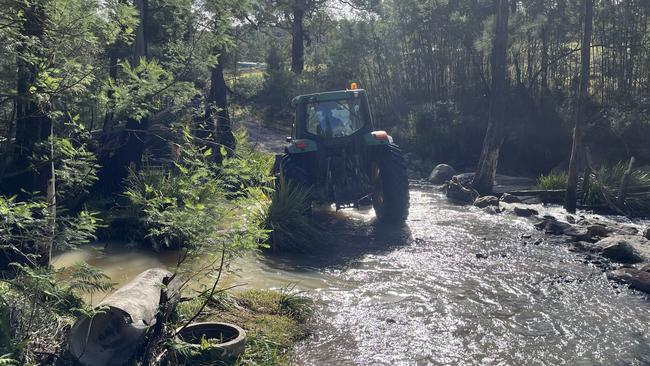 Rob Attard crossing the creek in a tractor. Picture: Tom McGann.