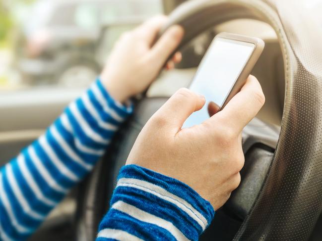 Woman driving car and texting message on smartphone, using mobile phone device while driving, dangerous and risky behavior in traffic