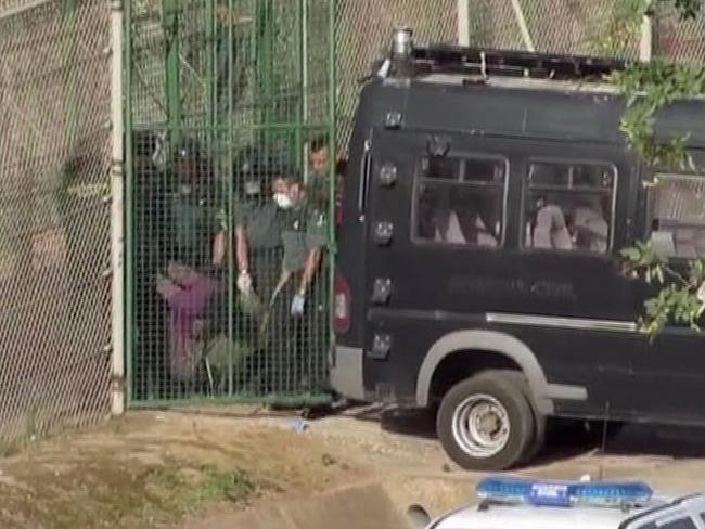 Spanish police carry the limp body of a 23-year-old Cameroonian through a border service gate, after apparently beaten while trying to climb the fence.