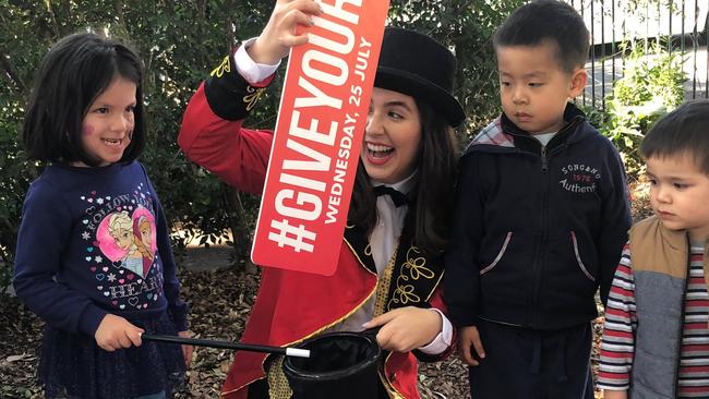 A Stardust Kids entertainer surprises children at St Anthony’s Family Care by pulling the DoSomething Day banner out of her hat.