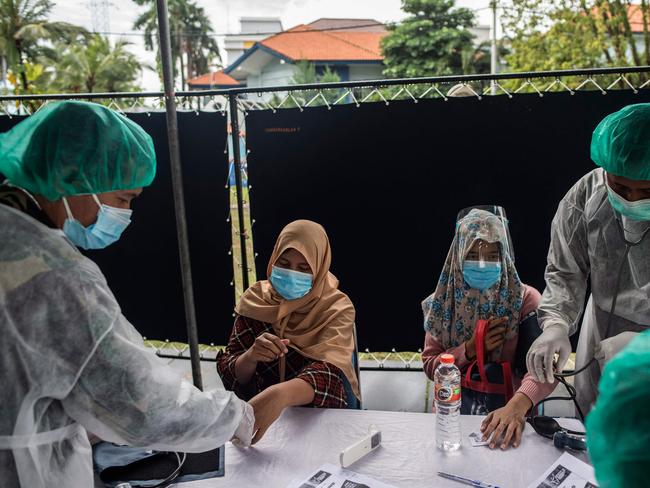 Health workers check on people before administering doses of the Sinovac Covid-19 vaccine during a mass vaccination at a housing area in Surabaya, Indonesia. Picture: AFP