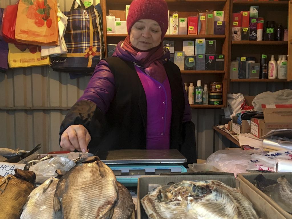 Irina Vakulina, 58, who used to live on the other side but switched to Russian citizenship in the early 2000s because she and her husband found a nicer house there, sells smoked fish and foreign-made perfume in a kiosk in Chertkovo, Russia. Picture: Nataliya Vasilyeva/AP