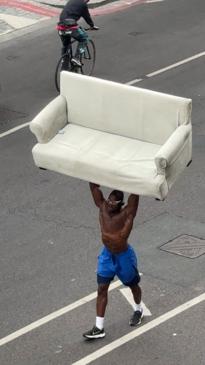 Strong man carries entire sofa through traffic