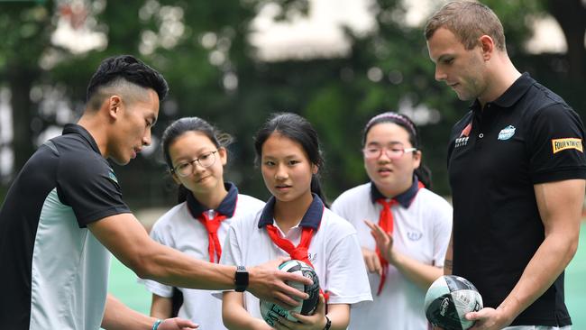 Chen Shaoliang (left) and Kyle Chalmers give Shanghai students some tips on handball technique.