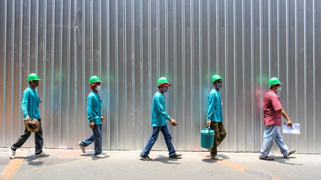 Construction workers wearing face masks and keeping safe distance amid fears of the spread of the COVID-19 coronavirus walk on a street in Bangkok.