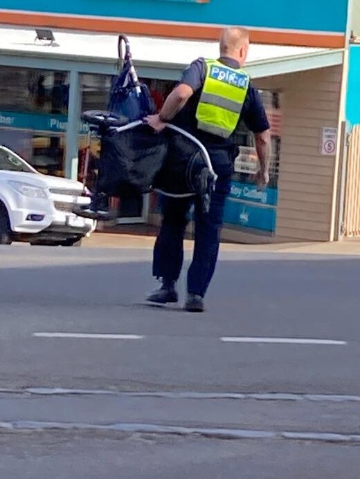 A police officer carries an abandoned pram just metrres from near where five people lost their lives in Daylesford. Picture: Damon Johnston