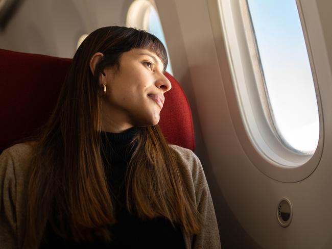 Young woman traveling by plane looking out the window