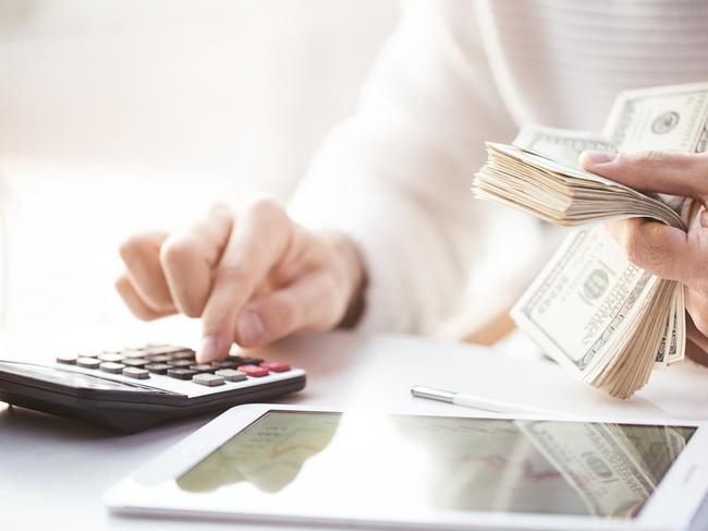 ESCAPE: ADVICE_ANNUAL TRAVEL INSURANCE, Sarah Nicholson -17FEB19. Hands counting us dollars with calculator and digital tablet Picture: iStock