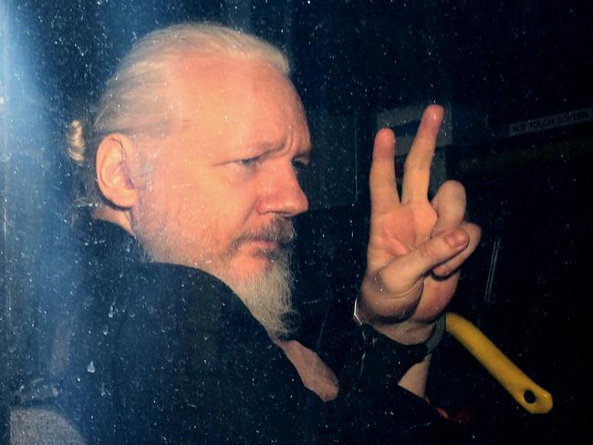 Julian Assange gestures to the media from a police vehicle on his arrival at Westminster Magistrates court. Picture: AP