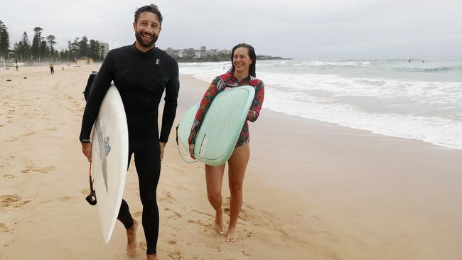 Sam Phillips and partner Kate Thomas surfing at Manly in Sydney on Monday. Picture: Nikki Short